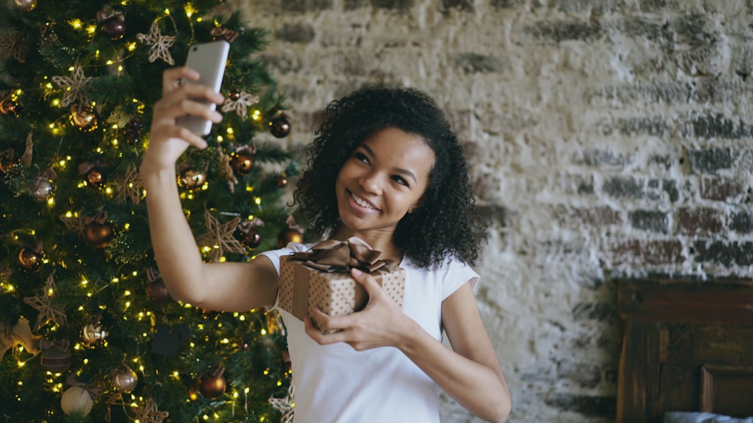 Woman taking a festive selfie beside a decorated Christmas tree